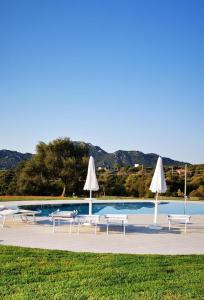 una piscina con mesas, sombrillas y sillas en Casa S'Ozastro, en Marinella
