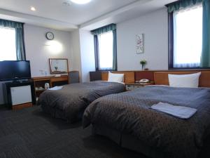 a hotel room with two beds and a flat screen tv at Terminal Hotel Matsuyama in Matsuyama