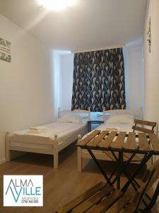 a room with two beds and a table at AlmaVille Mamaia in Mamaia Nord