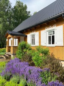una casa con flores púrpuras delante de ella en Wakacyjny Dom w Sakach, en Kleszczele