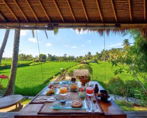 una tavola con cibo sopra con vista su un campo di MATHIS Retreat Ubud ad Ubud