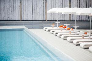 a swimming pool with white lounge chairs and umbrellas at Soho Grand Hotel in Azov