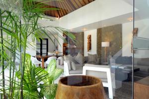 スミニャックにあるアカラ ヴィラの白い家具と植物のあるリビングルーム