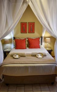 a bedroom with a large bed with red pillows at African Spirit Game Lodge in Manyoni Private Game Reserve