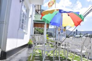 a table and chairs with a colorful umbrella at Inroma Holiday Resort in Nuwara Eliya