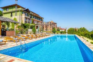 uma piscina com cadeiras e um edifício em Ampelo Resort em Kardanakhi