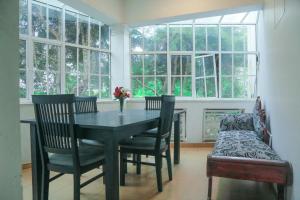 a dining room with a table and chairs and windows at Inroma Holiday Resort in Nuwara Eliya