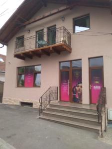 een gebouw met roze deuren en trappen ervoor bij Cazare REGIM HÔTELIER ZĂRNEŞTI in Zărneşti