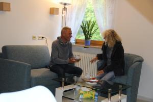 twee mensen zitten in een woonkamer bij Ferienwohnung Christine Trautner in Gößweinstein
