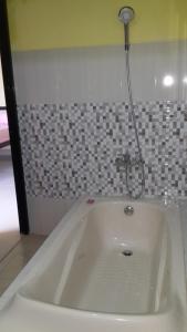 a white bath tub with a shower in a bathroom at Jepun Bali hotel negara in Negara