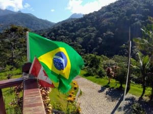 una bandera brasileña ondeando frente a una montaña en Flats vista bela com vista da montanha, en Paraty