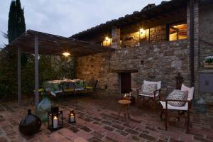 eine Terrasse mit einem Tisch, Stühlen und einem Kamin in der Unterkunft Premiere Apartments - Residenza Le Rose nel Chianti in Lornano