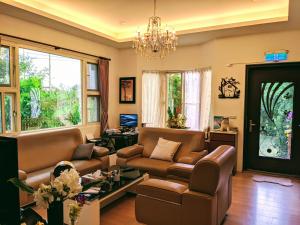a living room with leather furniture and a chandelier at Home-Link B&B in Fenglin