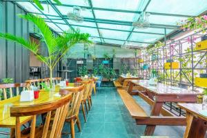 un restaurante con mesas de madera, sillas y plantas en FabHotel Astra Suites HSR Layout, en Bangalore