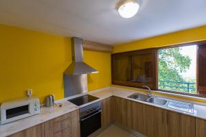 a kitchen with yellow walls and a sink and a microwave at Casa do Caminheiro in Lousã