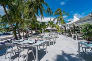 a row of tables and chairs on the beach with palm trees at La Vida Samui in Chaweng