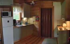 a kitchen with a white refrigerator and wooden floors at Kotalahden mökki in Kotalahti