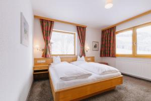 a bedroom with a bed and a window with red curtains at Haus Braunarl in Lech am Arlberg