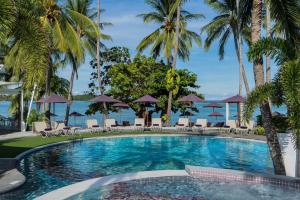 a swimming pool with palm trees and the ocean at La Vida Samui in Chaweng
