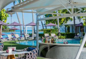 a poolside bar with tables and chairs next to a pool at La Vida Samui in Chaweng
