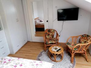 新瓦羅許的住宿－Apartman Slavica，客厅配有两把椅子和电视