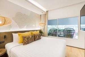 a bedroom with a bed with yellow pillows and a window at La Vida Samui in Chaweng