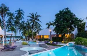 a swimming pool with chairs and palm trees at night at La Vida Samui in Chaweng