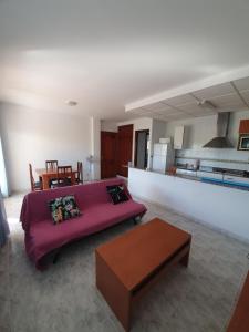 sala de estar con sofá púrpura y mesa en Apartaments Marinera, en L'Eucaliptus