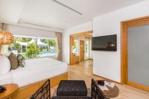 a living room with a white couch and a tv at La Vida Samui in Chaweng