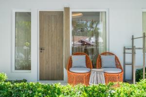 two wicker chairs sitting on a porch next to a door at La Vida Samui in Chaweng