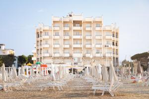 a beach with chairs and a building in the background at Hotel Life in Rimini
