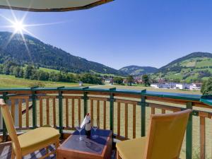 a table and chairs on a balcony with a view of the mountains at Hotel Harfenwirt in Niederau