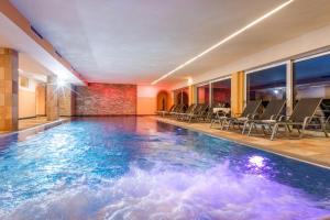 a pool in a hotel with chairs and a table at Harmony Hotel Harfenwirt in Niederau