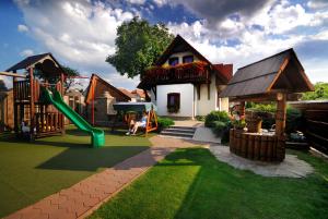 einen Hinterhof mit einem Spielplatz mit Rutsche und einem Haus in der Unterkunft Apartmánový dom Slniečko in Liptovský Ján