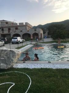 un groupe de personnes assises dans une piscine dans l'établissement residenza monarka, à Marina di Davoli