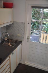 uma cozinha com uma porta com uma janela e um lavatório em Rob's Cottage em Schoorl