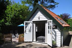 um pequeno barracão branco com um telhado verde em Rob's Cottage em Schoorl