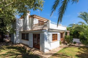 a white house with a balcony and palm trees at Villa Beach Palmitos in Can Picafort