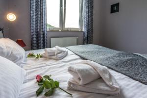 Una cama blanca con toallas y una rosa. en Apartamenty Izerskie, en Świeradów-Zdrój