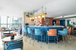 a restaurant with a blue bar with chairs and tables at Prima Millennium in Ra‘ananna