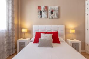 a bedroom with a large white bed with red pillows at Apartamento Sofia Ronda Center in Ronda