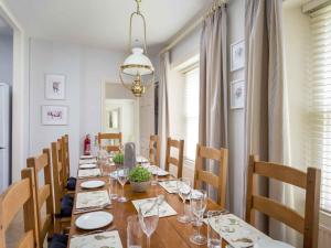 a dining room with a long wooden table with chairs at Lakeside House in Yanworth