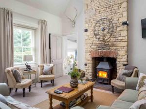 a living room with a stone fireplace and a table at Lakeside House in Yanworth
