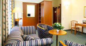 um quarto de hotel com um sofá, cadeiras e uma mesa em Victor's Residenz-Hotel Gera em Gera