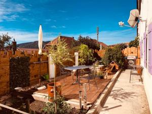 una terrazza in legno con tavolo in un cortile posteriore di LE 13, Charmant appartement de 2 pièces à Lignerolle a Lignerolle