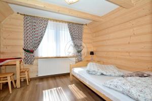 a bedroom with a bed and a table and a window at Willa Swajnos in Zakopane
