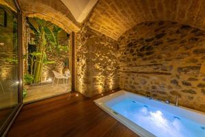 a bath tub in a room with a stone wall at MORAMUSA Charme Apartment in Cefalù