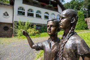 een standbeeld van twee kinderen die voor een gebouw staan bij Märchenwald Altenberg B&B Hotel in Odenthal