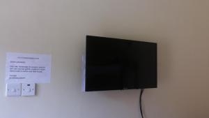 einen Flachbild-TV, der an einer Wand hängt in der Unterkunft Leam Guesthouse in Moyo
