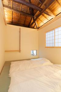 Duas camas num quarto com tectos em madeira em Trawl Guesthouseトロールゲストハウス em Koshigoe